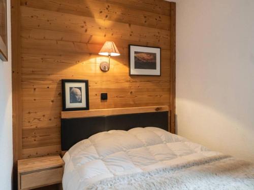 Un dormitorio con una cama con una pared de madera. en Bel appartement rénové, 4 pers, balcon, casier à skis - FR-1-291-865, en Valmorel