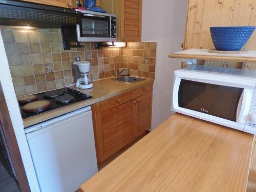 une petite cuisine avec un micro-ondes et une cuisinière dans l'établissement Lumineux studio savoyard avec balcon exposé SUD - FR-1-458-114, au Grand-Bornand