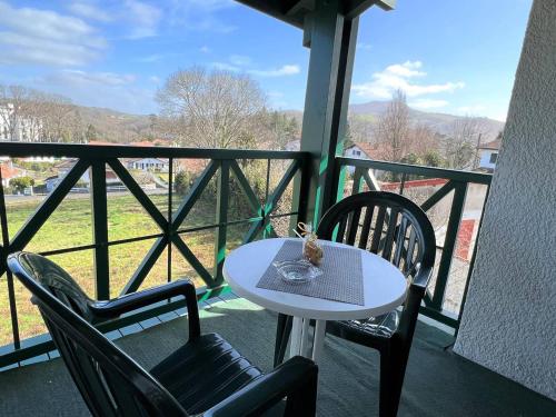une table et deux chaises sur un balcon avec vue dans l'établissement Studio Lys à Cambo-les-Bains, 2 pers, Terrasse & Parking, Proche Thermes, Animaux Acceptés - FR-1-495-98, à Cambo-les-Bains