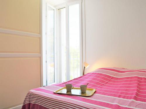 - 2 tasses sur un plateau sur un lit avec une fenêtre dans l'établissement Appartement Climat. 4 pers. avec Parking Privatif au Lavandou, Proche Centre et Plage - FR-1-251-390, au Lavandou