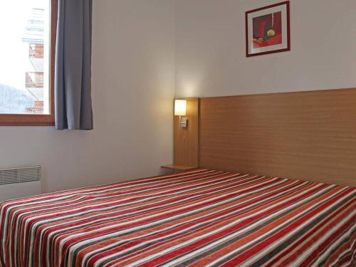 une chambre avec un lit avec une couverture rayée dans l'établissement Les Orres 1800: Appart 3 pièces, Piscine, WiFi, Animaux admis - FR-1-322-431, aux Orres