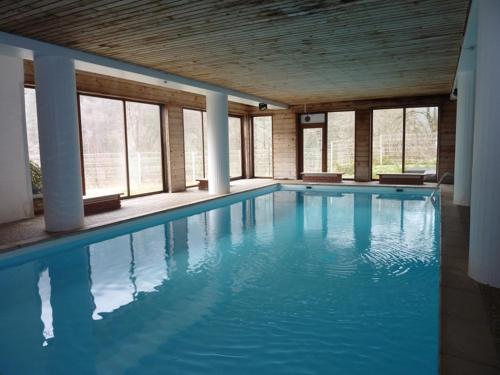 une grande piscine avec de l'eau bleue dans un immeuble dans l'établissement Duplex cosy 7 pers proche pistes avec piscine - FR-1-573-34, à Saint-Jean-dʼAulps
