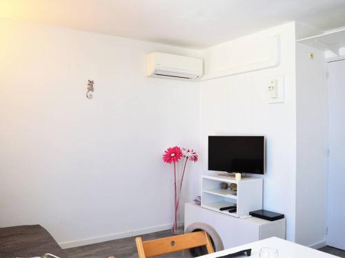 - un salon avec une télévision et un vase de fleurs dans l'établissement Appartement Climat. 4 pers. avec Parking Privatif au Lavandou, Proche Centre et Plage - FR-1-251-390, au Lavandou