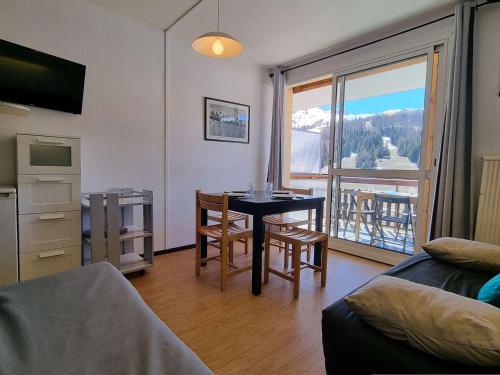 d'un salon avec une table et un balcon. dans l'établissement Studio cosy proche pistes avec Wifi, parking et animaux admis - FR-1-525-190, à Saint-Étienne-en-Dévoluy