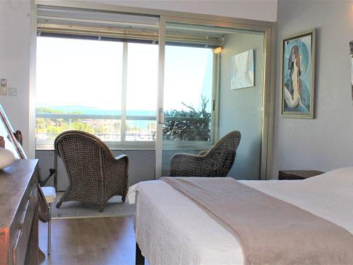 une chambre avec un lit et deux chaises et une fenêtre dans l'établissement Appartement 3P avec terrasse et parking, Villeneuve-Loubet Plage - FR-1-252A-63, à Villeneuve-Loubet