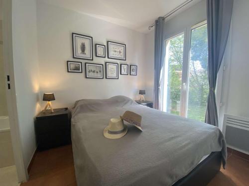 un lit avec un chapeau et un livre dessus dans l'établissement Sainte-Maxime: Appart 3P climatisé avec piscine, parking privé et jardin calme - FR-1-226-471, à Sainte-Maxime