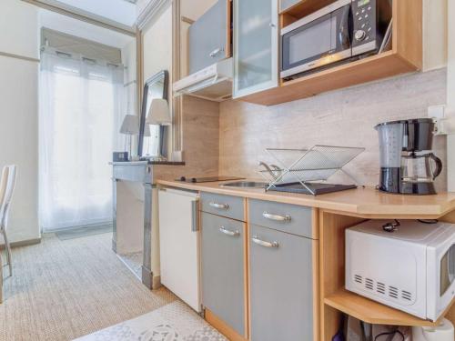 une cuisine avec des armoires en bois et un comptoir dans l'établissement Appartement Centre Cauterets 4/6 pers avec Balcon, Cuisine Équipée et Local à Skis - FR-1-401-226, à Cauterets