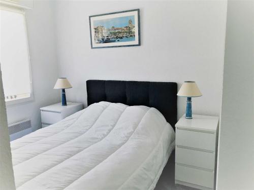 ein weißes Schlafzimmer mit einem Bett mit einem schwarzen Kopfteil und zwei Lampen in der Unterkunft Appartement Saint-Jean-de-Luz, 3 pièces, 5 personnes - FR-1-4-612 in Saint-Jean-de-Luz