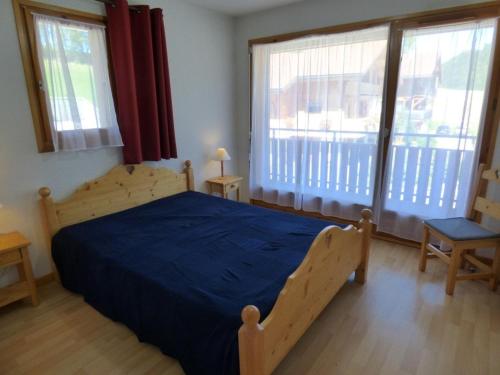a bedroom with a bed with a blue bedspread and two windows at Appartement Saint-Jean-de-Sixt, 3 pièces, 6 personnes - FR-1-458-134 in Saint-Jean-de-Sixt