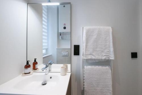 La salle de bains blanche est pourvue d'un lavabo et d'un miroir. dans l'établissement Opéra 8 - Superbe studio refait à neuf proche place des Terreaux, à Lyon