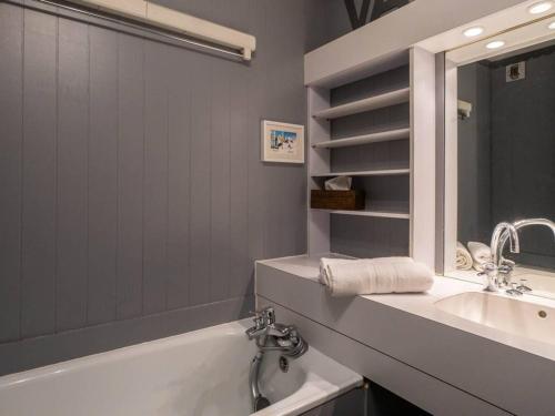 uma casa de banho com uma banheira, um lavatório e um espelho. em Studio Valmorel, 1 pièce, 4 personnes - FR-1-291-870 em Valmorel