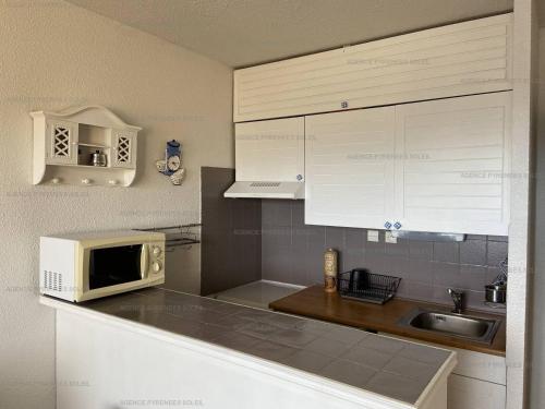 une cuisine avec un micro-ondes et un évier dans l'établissement Studio cabine cosy avec balcon Sud, parking et WiFi aux Angles - FR-1-295-131, aux Angles