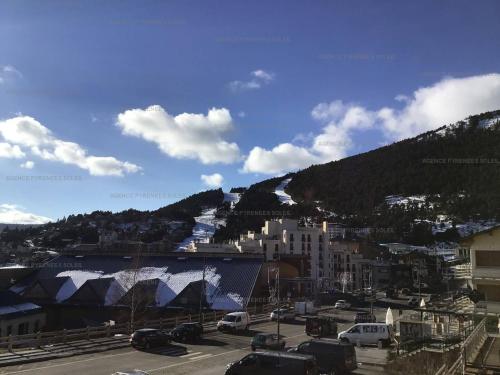 - un parking avec des voitures garées devant une montagne dans l'établissement Studio cabine 4 pers, proche pistes, balcon, ascenseur, centre - FR-1-295-181, aux Angles