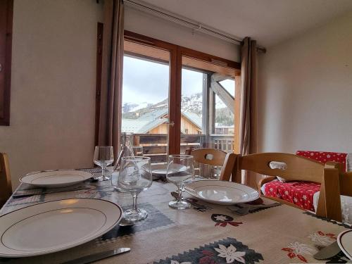 - une table à manger avec des assiettes et des verres à vin dans l'établissement Appartement 2 pièces, parking, proche télésiège - Le Dévoluy - FR-1-525-226, à Saint-Étienne-en-Dévoluy
