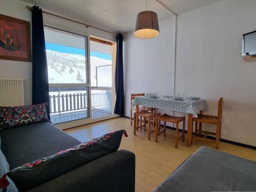 un salon avec un canapé et une table avec des chaises dans l'établissement Studio cosy, front de neige, proche télésiège Le Jas, pour 4 personnes – SuperDévoluy. - FR-1-525-230, à Saint-Étienne-en-Dévoluy