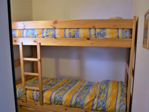 a wooden bunk bed with a yellow and blue sheets at Appartement Risoul, 1 pièce, 4 personnes - FR-1-330-542 in Risoul