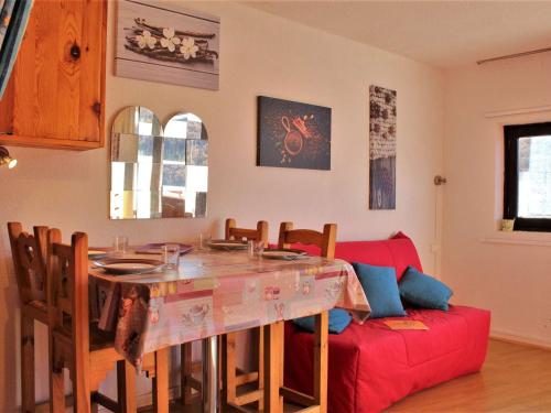 un salon avec une table et un canapé rouge dans l'établissement Studio cosy à Risoul 1850 - 4 couchages, pied des pistes, parking, balcon - FR-1-330-543, à Risoul