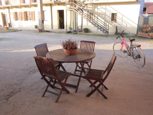 a wooden table with three chairs and a bike at Al Casale B&B in Cherasco