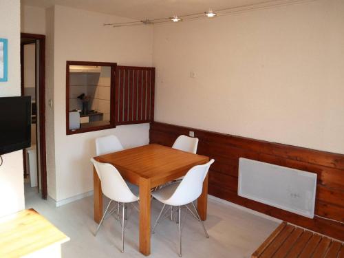une salle à manger avec une table en bois et des chaises blanches dans l'établissement Grand studio skis aux pieds avec balcon, pour 4/5 pers, proche toutes commodités ! - FR-1-322-459, aux Orres