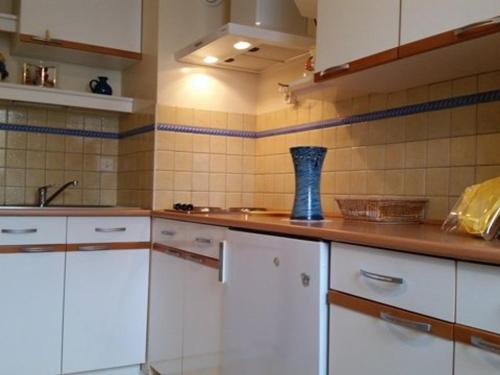 une cuisine avec des placards blancs et un vase bleu sur le comptoir dans l'établissement Studio ski, 4 pers, parking gratuit, proche pistes - FR-1-602-97, à Arette