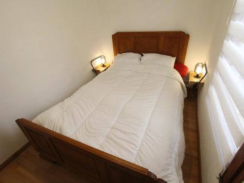- une chambre avec un lit avec des draps blancs et 2 lampes dans l'établissement T2 à Luchon avec Parking, Wifi et Animaux admis - FR-1-313-207, à Luchon