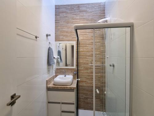La salle de bains est pourvue d'un lavabo et d'une douche. dans l'établissement Curta Praia de Armação Casa Hortênsia, à Penha