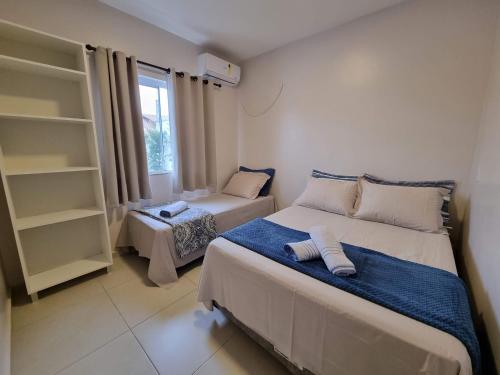 a small bedroom with two beds and a window at Curta Praia de Armação Casa Hortênsia in Penha