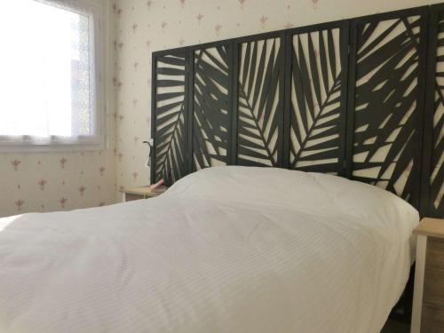 1 dormitorio con cama blanca y cabecero negro en Appartement Saint-Gilles-Croix-de-Vie, 2 pièces, 4 personnes - FR-1-224-783, en Saint Gilles Croix de vie