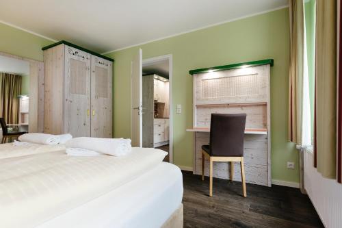 a bedroom with a bed and a desk and a chair at Insulaner Ferienwohnungen in Helgoland