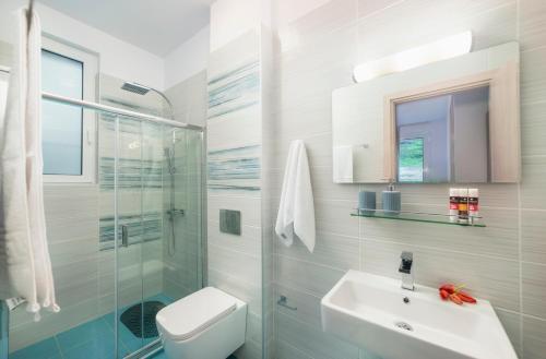 een badkamer met een wastafel, een toilet en een douche bij Costa Maris Villa in Georgioupoli