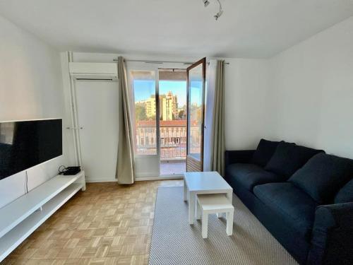 uma sala de estar com um sofá azul e uma televisão em Petit cocon avec Balcon au centre de Marseille em Marselha