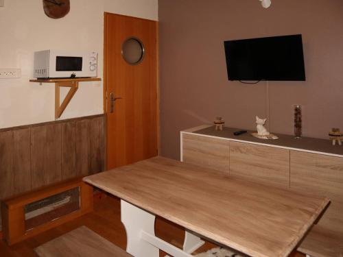- un salon avec une table en bois et une télévision dans l'établissement Studette rénovée proche pistes et centre Les Orres - FR-1-322-465, aux Orres