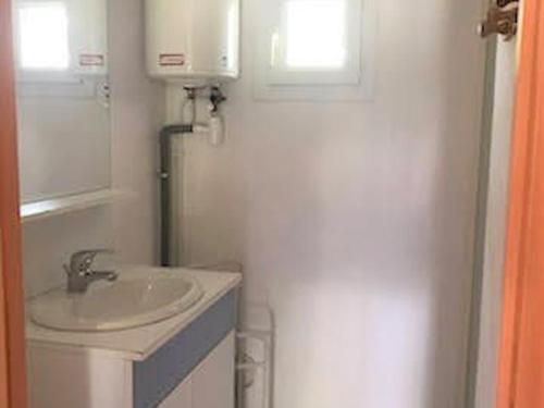 une salle de bain blanche avec un lavabo et un miroir dans l'établissement Maison 2 chambres avec piscine, tennis, et plus - idéal pour 4 personnes à Vallon-Pont-d'Arc - FR-1-382-179, à Vallon-Pont-dʼArc
