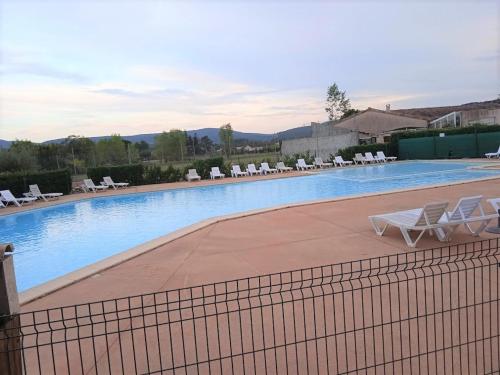 une piscine avec des chaises longues et une clôture dans l'établissement Maison 2 chambres avec piscine, tennis, et plus - idéal pour 4 personnes à Vallon-Pont-d'Arc - FR-1-382-179, à Vallon-Pont-dʼArc