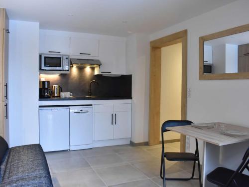 une cuisine avec des armoires blanches et une table et une salle à manger dans l'établissement Studio Montagne Rénové, 2 Pers, Proche Pistes et Commerces, Méribel - FR-1-180-572, à Les Allues