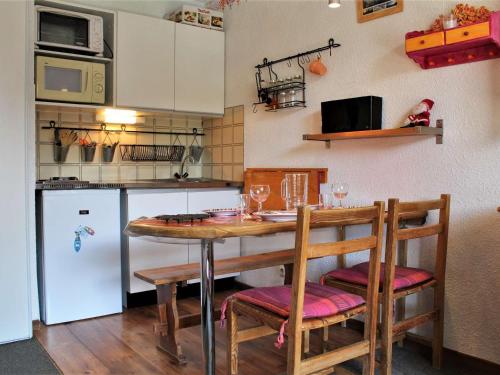une cuisine avec une table, des chaises et un réfrigérateur dans l'établissement Studio cosy pour 4 au centre de Risoul, proche commerces et pistes - FR-1-330-550, à Risoul