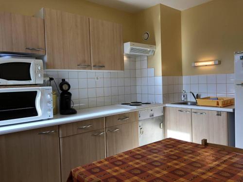 - une cuisine avec des placards en bois et un four micro-ondes dans l'établissement Studio 6 pers, à côté des pistes, parking & ascenseur, casier à skis, proche commerces - FR-1-602-101, à Arette