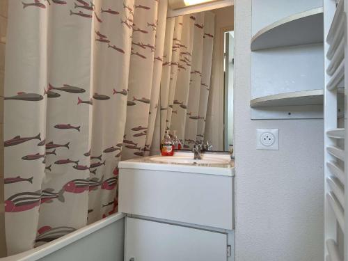 La salle de bains est pourvue d'un lavabo et d'un rideau de douche avec du poisson. dans l'établissement Appartement confortable 2 pièces avec balcon et parking, proche plage - FR-1-224-784, à Saint-Hilaire-de-Riez