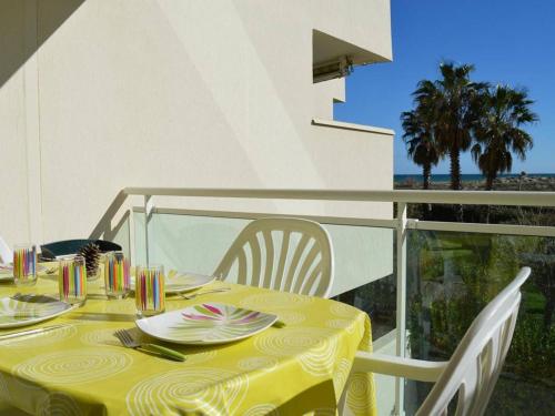 une table avec un chiffon de table jaune sur un balcon dans l'établissement Appartement moderne 6 pers avec terrasse, parking et piscine à Saint-Cyprien - FR-1-225D-129, à Saint-Cyprien