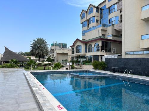 uma piscina em frente a um edifício em Hôtel Sancta Maria em Lomé