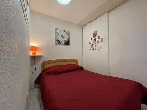 Cette petite chambre comprend un lit avec des draps rouges. dans l'établissement Appart 3 Chambres, 6 Pers, Terrasse, Parking, Plage à proximité - FR-1-379-142, à Vieux-Boucau-les-Bains