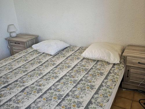 um quarto com uma cama com uma almofada e uma mesa de cabeceira em Appartement Le Barcarès, 2 pièces, 5 personnes - FR-1-195-88 em Le Barcarès