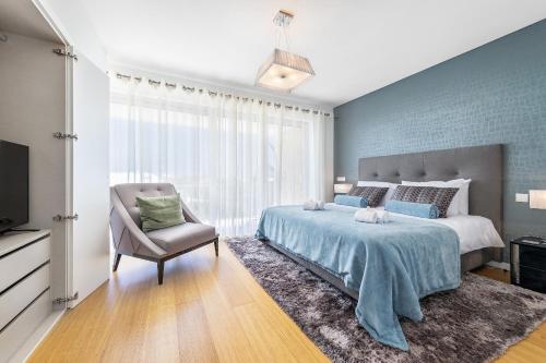 een slaapkamer met een groot bed en een stoel bij ELLE Design Villa by OCvillas in Albufeira