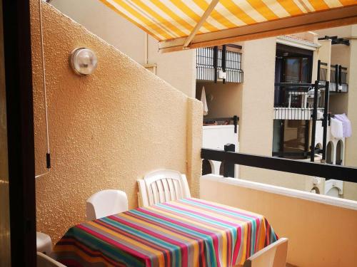 une table avec un tissu de table coloré sur un balcon dans l'établissement Appartement 2 Pièces avec Terrasse, Accès Piscine et Activités Sportives - 4 Couchages, Clim en Option - FR-1-195-89, au Barcarès