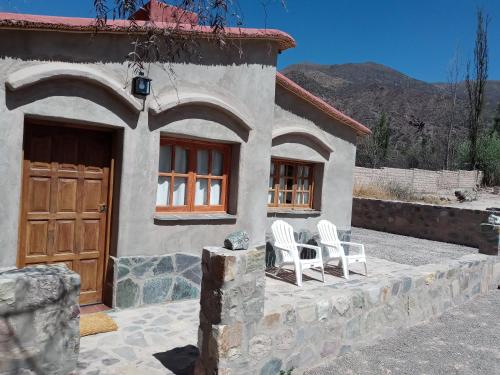 una casa con dos sillas blancas delante en Cabaña Flor de Cardón-Juella. en Juella