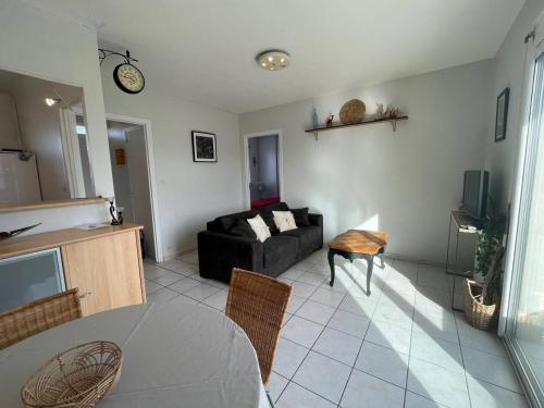 un salon avec un canapé noir et une table dans l'établissement Appartement 2 pièces avec balcon, parking, à 2 pas de la plage - FR-1-225D-133, à Saint-Cyprien