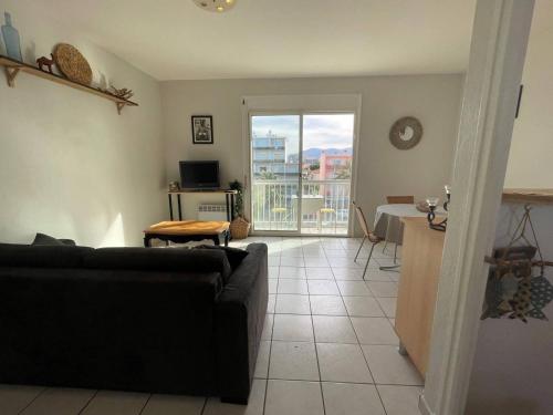 un salon avec un canapé noir et une table dans l'établissement Appartement 2 pièces avec balcon, parking, à 2 pas de la plage - FR-1-225D-133, à Saint-Cyprien