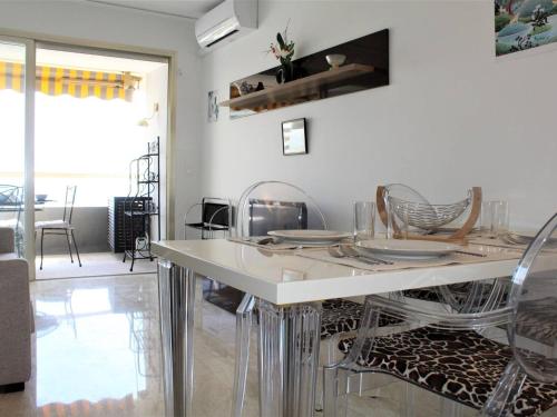 une salle à manger avec une table et des chaises blanches dans l'établissement Studio calme, climatisé et équipé avec terrasse vue mer - 2 couchages - FR-1-252A-67, à Villeneuve-Loubet