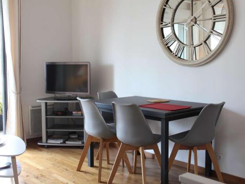 une table à manger avec des chaises et une horloge murale dans l'établissement Studio moderne 4 pers au centre de La Baule avec terrasse et garage, proche plage et commerces - FR-1-245-162, à La Baule