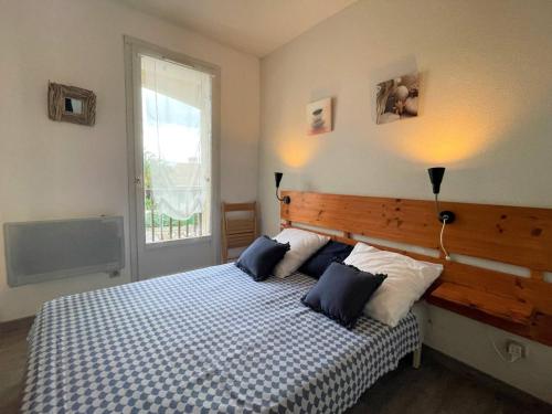 une chambre avec un lit avec des oreillers bleus et blancs dans l'établissement Appartement cosy avec piscine, terrasse et parking - 250m de la plage - 6 pers. - FR-1-225D-141, à Saint-Cyprien